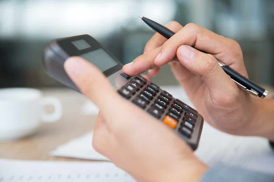 Pessoa fazendo contas com uma calculadora, com dicas de gestão para fotógrafos.