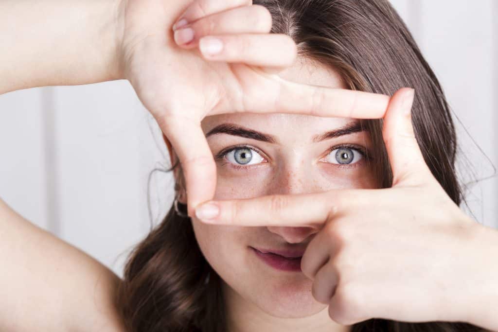 Mulher fazendo sinal de enquadramento com as mãos em frente aos olhos